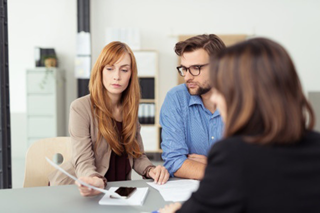 Iamge of three people in meeting and discussing a document